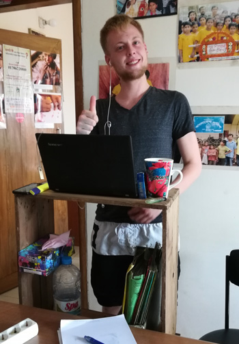 Domenic at his homemade back-friendly desk - necessity if you lack a proper chair to work.